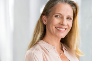 a woman smiling after receiving dental implants that improved her smile