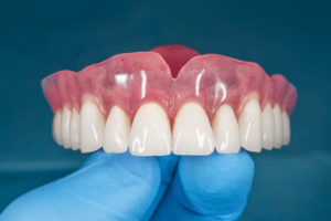 a full denture being shown held up by a doctor